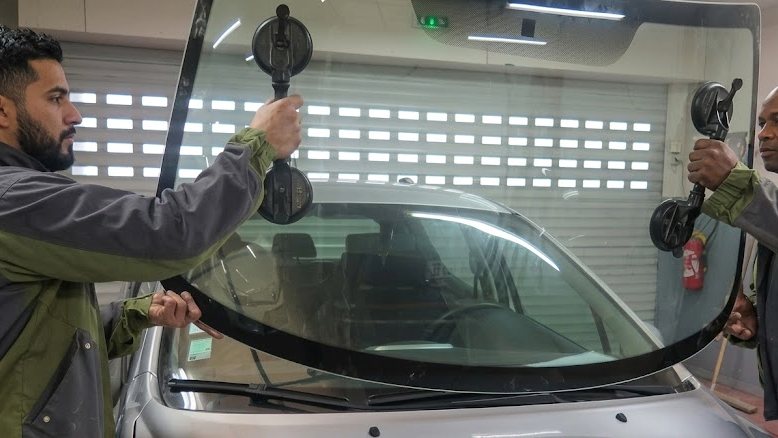 Techniciens posant un pare-brise neuf à l’atelier de Gravelotte